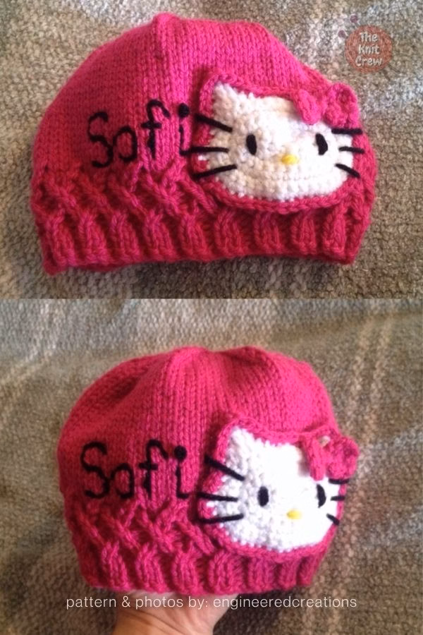 A close-up of a vibrant pink knitted beanie featured in a crochet and knit roundup from The Knit Crew. The hat features an intricate braided cable pattern along the brim and a large, handmade Hello Kitty applique on the side. The white kitty face is accented with a pink bow and black whiskers. To the left of the applique, the name "Sofi" is embroidered in black cursive yarn.