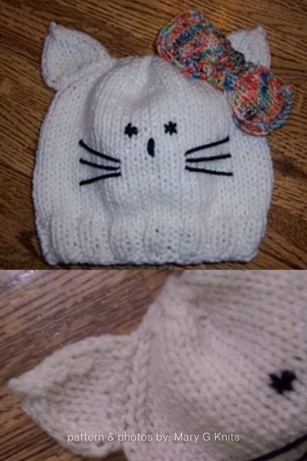 A white knitted baby beanie with cat ears, featured in a curated gift roundup from The Knit Crew. The hat includes embroidered black whiskers and eyes, and it is topped with a large, colorful variegated yarn bow in shades of blue, pink, and orange. The bottom image shows a close-up detail of the pointed knit ear and stitch work.
