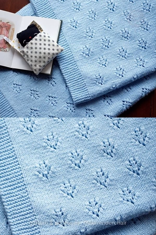 A close-up view of a bright blue knitted blanket featuring small, repeating leafy eyelet pointelle motifs and a ribbed border. A small black cat plush toy tucked in a book sits nearby. Text at the bottom reads: "pattern & photos by: thelavenderchair". Curated by Ariana of TheKnitCrew.